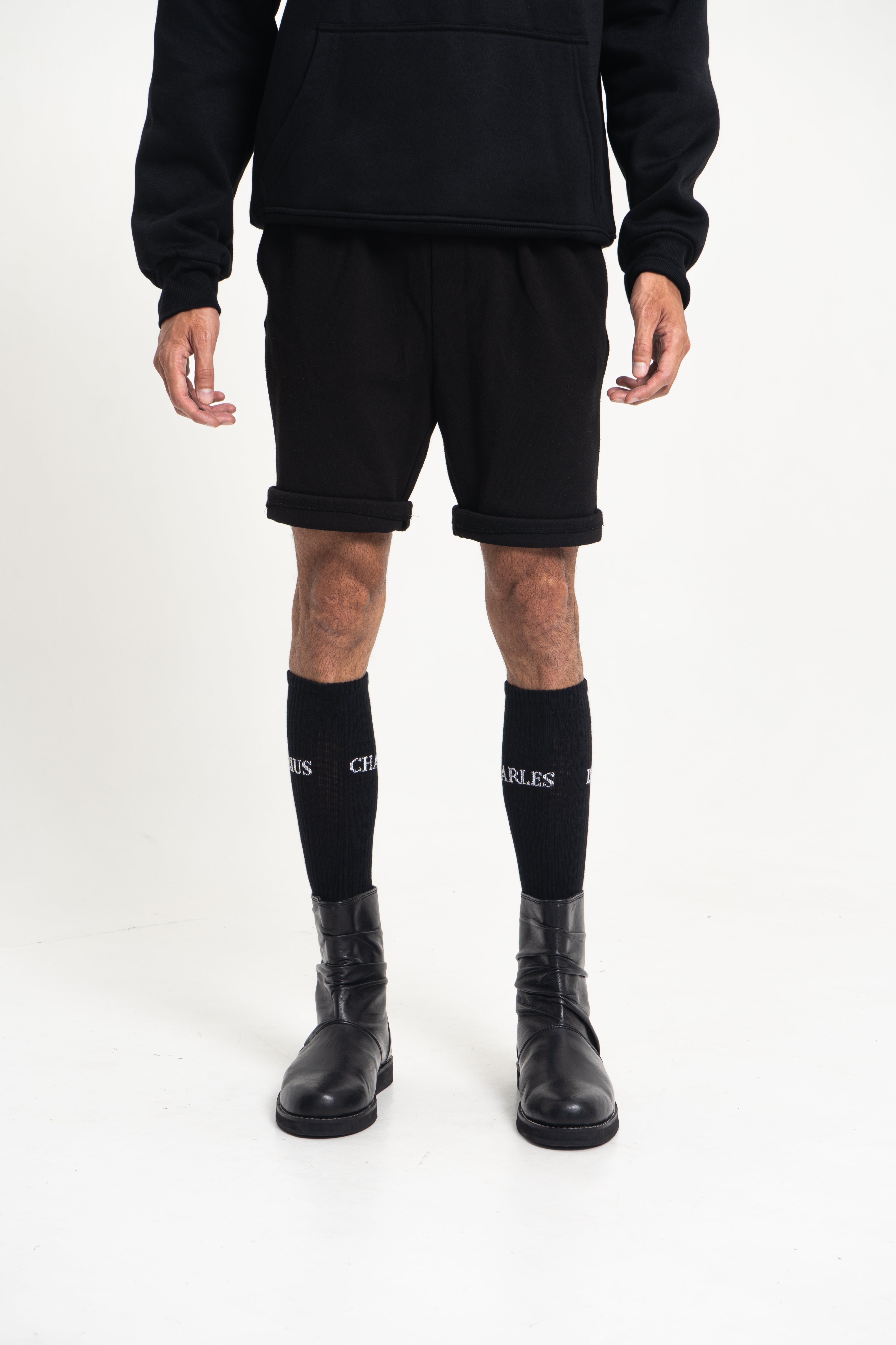 Male model wearing Charles Darius High Socks – full body view, black cotton knit