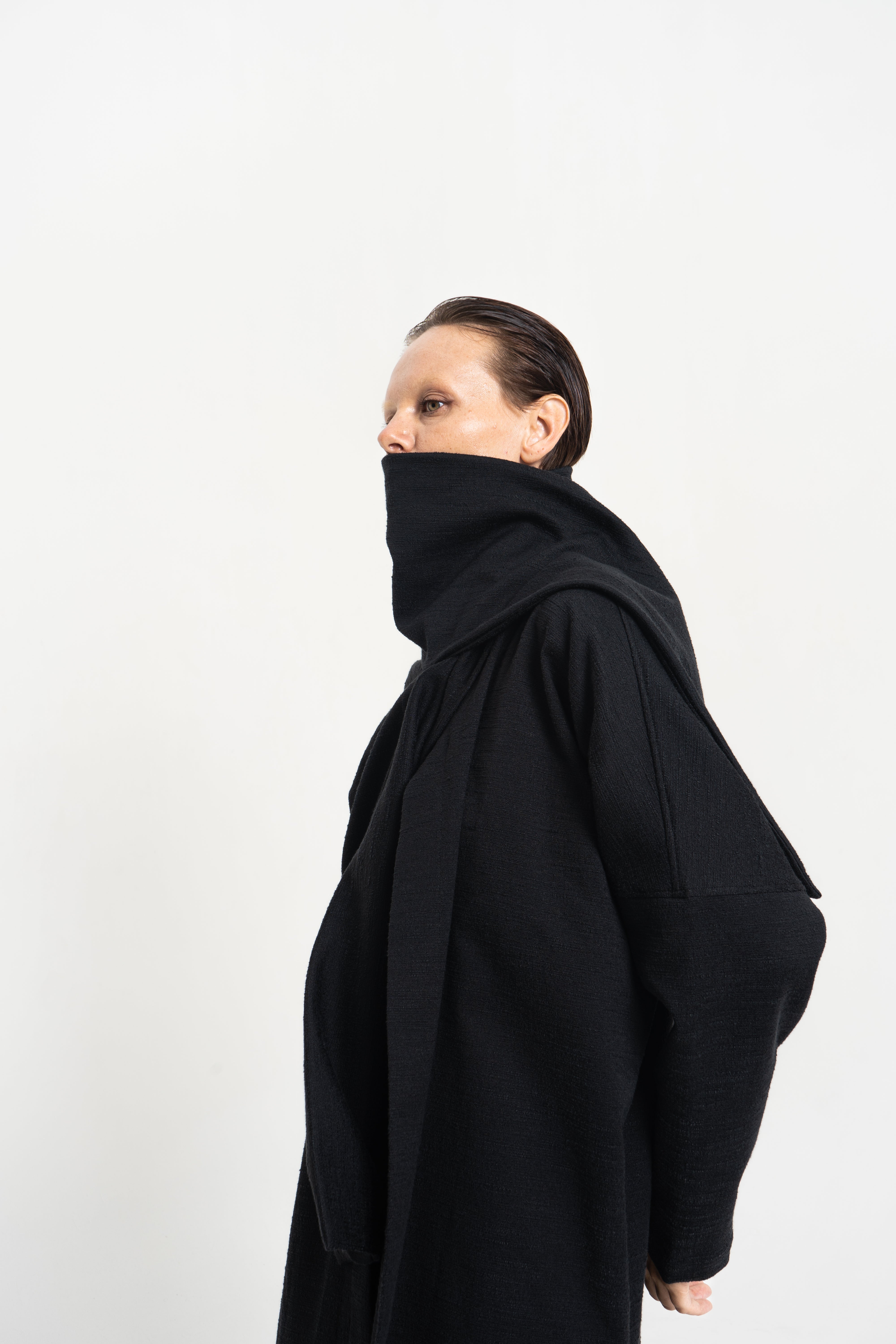 Black sculptural knit coat close-up on model, Charles Darius Ready-to-Wear Collection campaign.