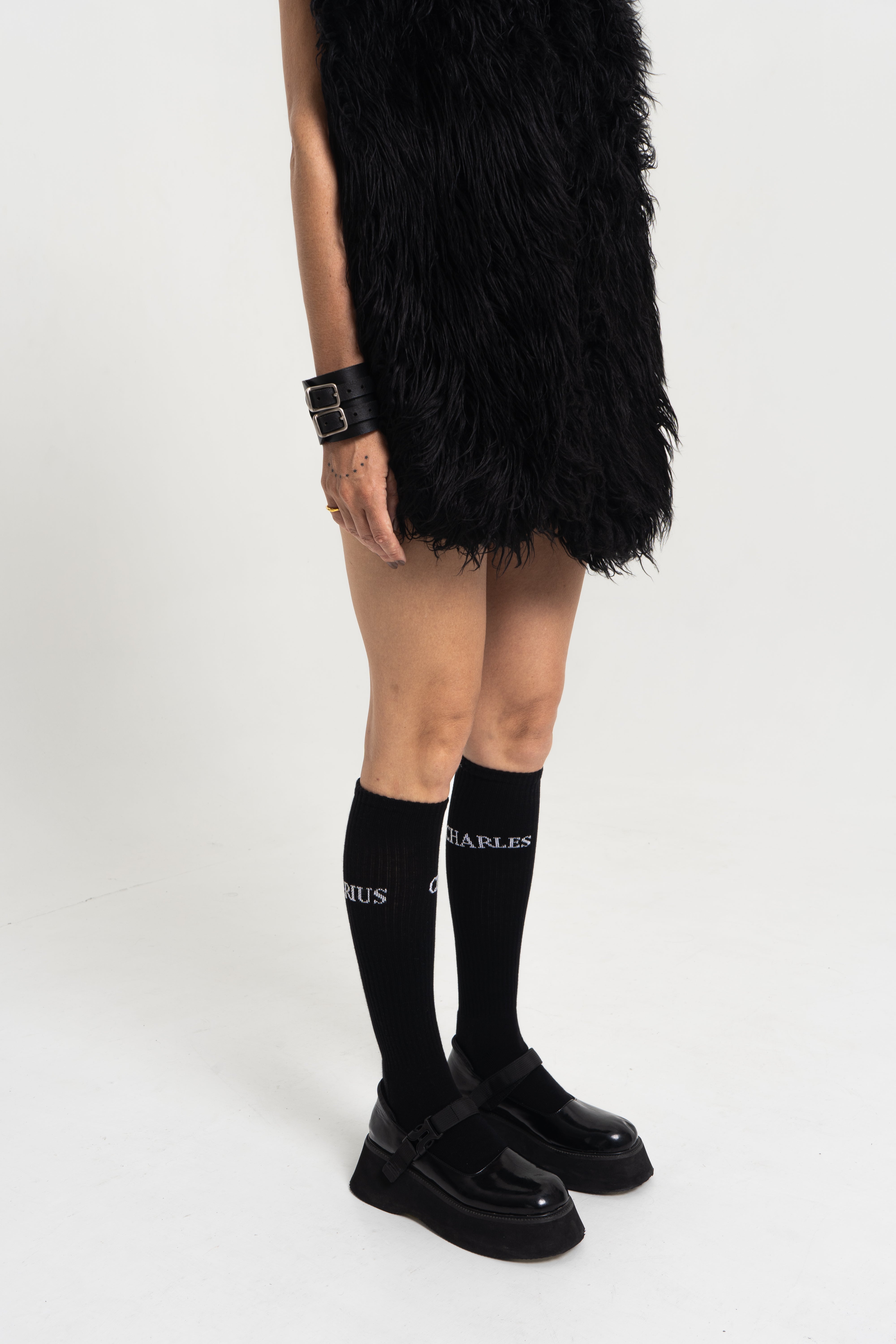 Female model wearing Charles Darius High Socks in black, side view on white background